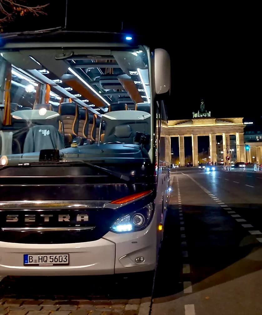 Reisebus von BerlinBus.DE bei Nacht vor dem Brandenburger Tor in Berlin